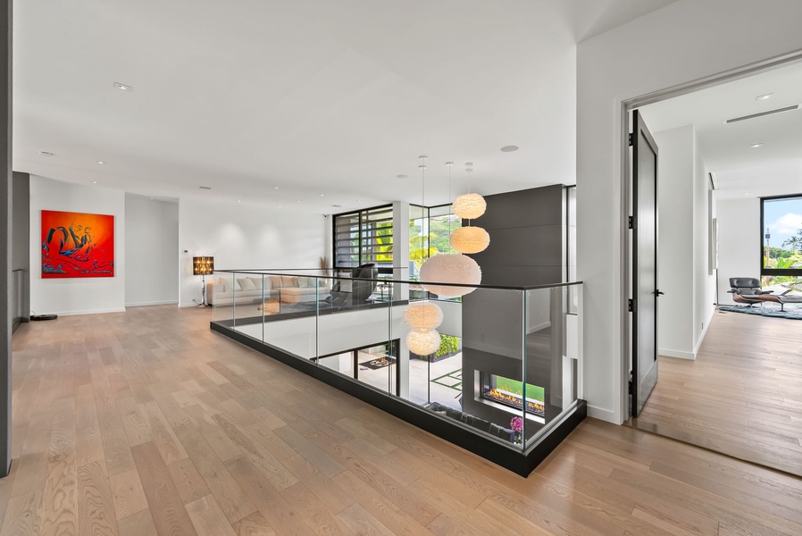 Open upper level with glass railing, warm wood floors, and a clean, light-filled modern design.