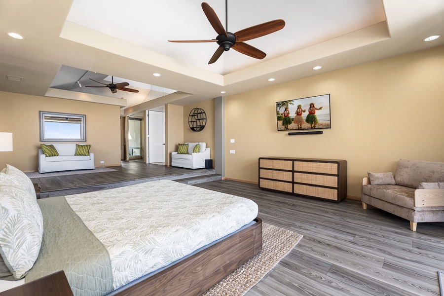 Unwind in this spacious primary bedroom where tropical breezes from ceiling fans complement the ocean-inspired decor and plush seating nook.