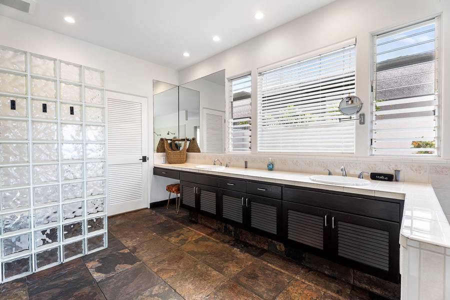 Primary bathroom with dual vanities and dark wood accents, designed for post-beach unwinding with a spa-like feel.
