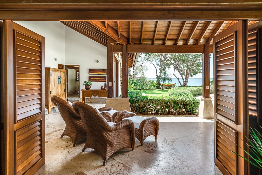 Enjoy the open-air living space with comfortable seating, offering seamless access to the lush garden and ocean views.