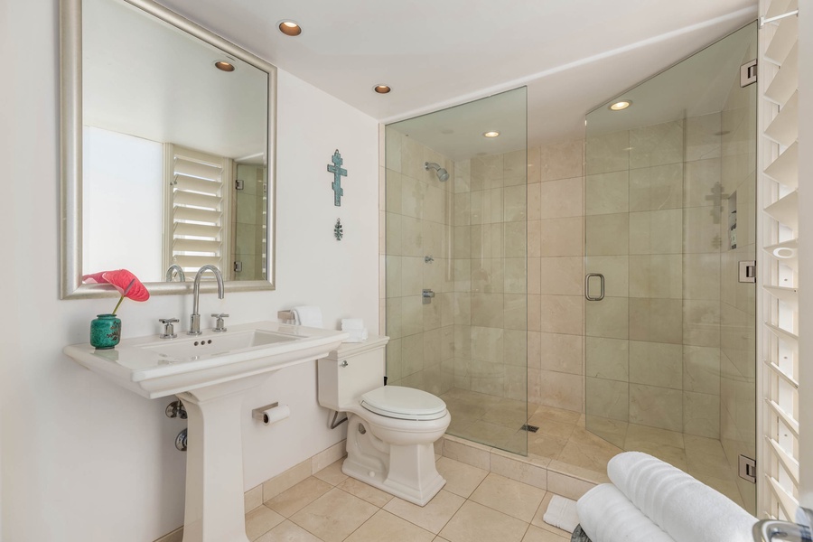 Ensuite bath with a walk-in shower in a glass enclosure, single sink and ample vanity space.