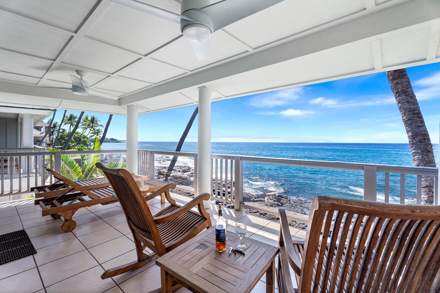 Covered primary bedroom lanai with lounge seating and uninterrupted views of the ocean’s edge.
