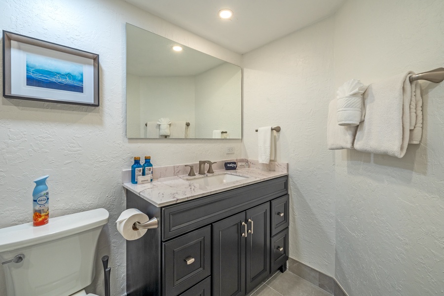 A cozy and well-lit bathroom with a dark wood vanity, topped with a large mirror reflects the soft lighting