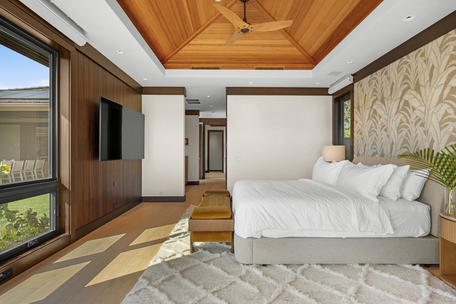Primary Suite #1: Rest in your spacious bedroom featuring warm wood tones, pristine linens, and natural light streaming through floor-to-ceiling windows.
