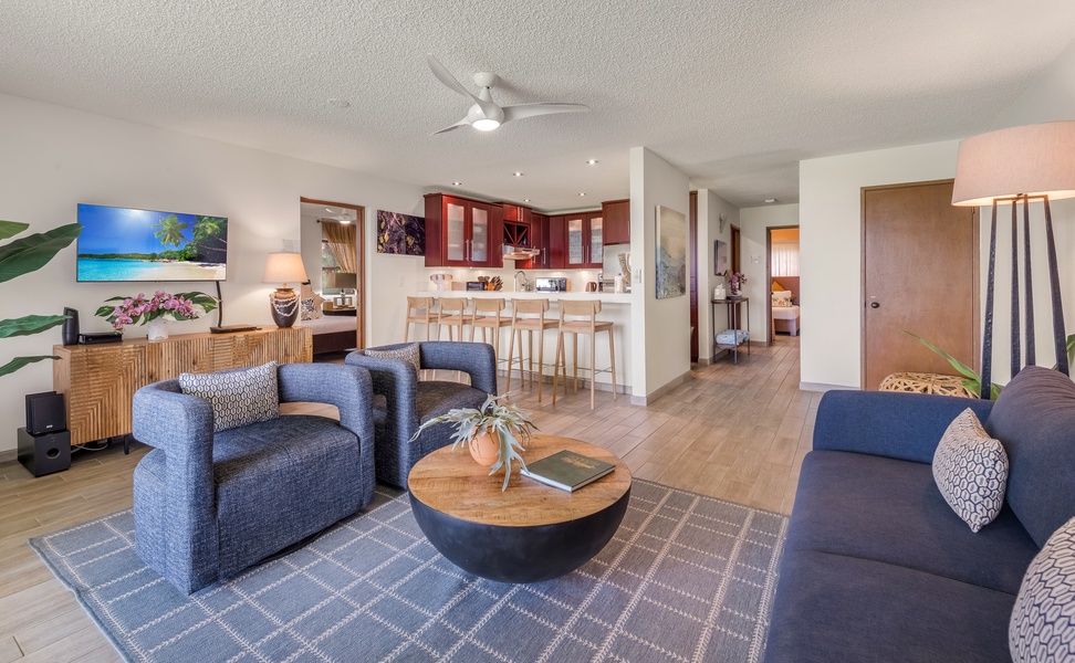 Relax in your spacious open-concept living area with comfortable navy seating, modern kitchen, and tropical touches that create the perfect home base.