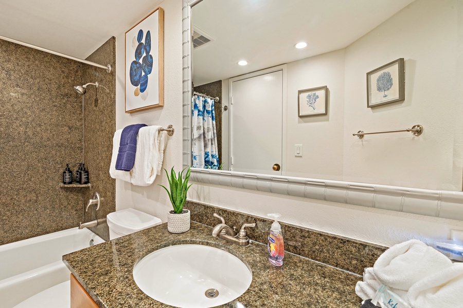 The bathroom includes a stylish granite vanity, a modern sink, and bright lighting, offering a comfortable and elegant space to get ready for your day.