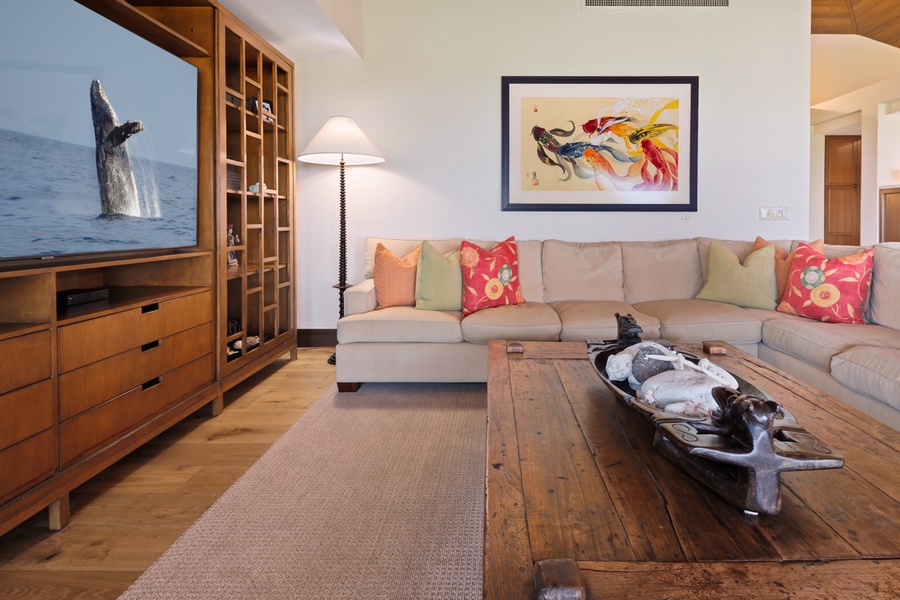 Sink into plush seating surrounded by warm wood tones and vibrant art, perfect for movie nights or quiet moments.