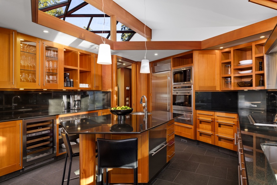 Your gourmet kitchen features rich wood cabinetry, granite counters, and professional-grade appliances with skylights flooding the space in natural light.