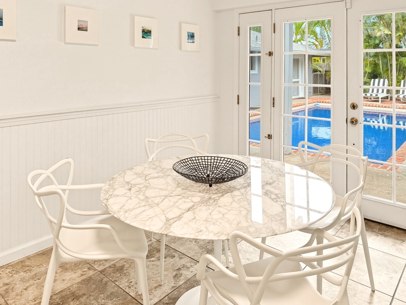 Your elegant breakfast nook features a marble table with poolside views through French doors, perfect for morning coffee or evening meals.