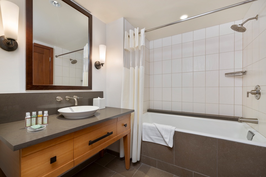 Unwind in your elegant bathroom featuring a deep soaking tub, rainfall shower, and premium amenities for ultimate relaxation.