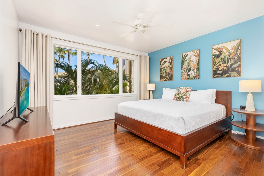 Wake up to swaying palms outside your window in this serene bedroom, where tropical artwork and soothing blue accents create your perfect island retreat.