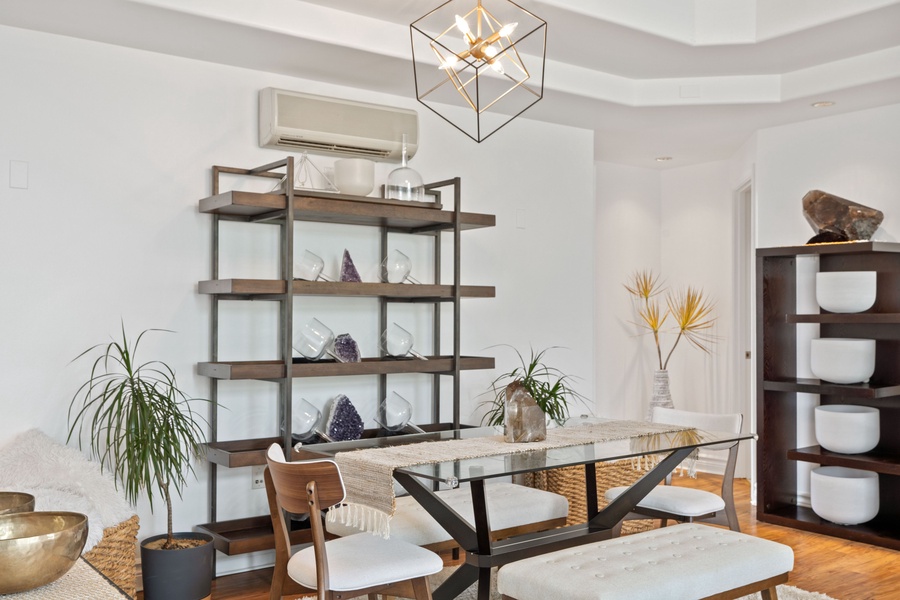 Metal-framed shelves adorned with decor items and plants enhance the room's ambiance, all set with a split-type AC in the main area for a cozy getaway.