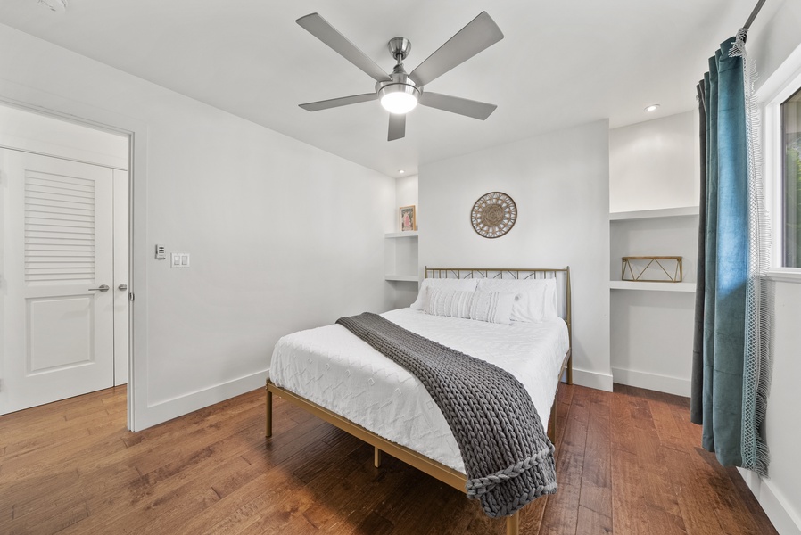 Modern bedroom with sleek design, hardwood floors, and built-in shelving.