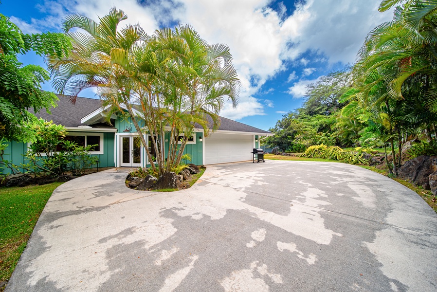 Welcoming driveway framed by tropical palms, offering ample parking and a warm first impression upon arrival.