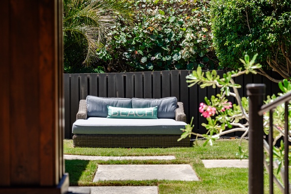 A cozy outdoor seating area featuring a comfortable cushioned sofa, perfect for relaxing in the garden with a refreshing breeze.