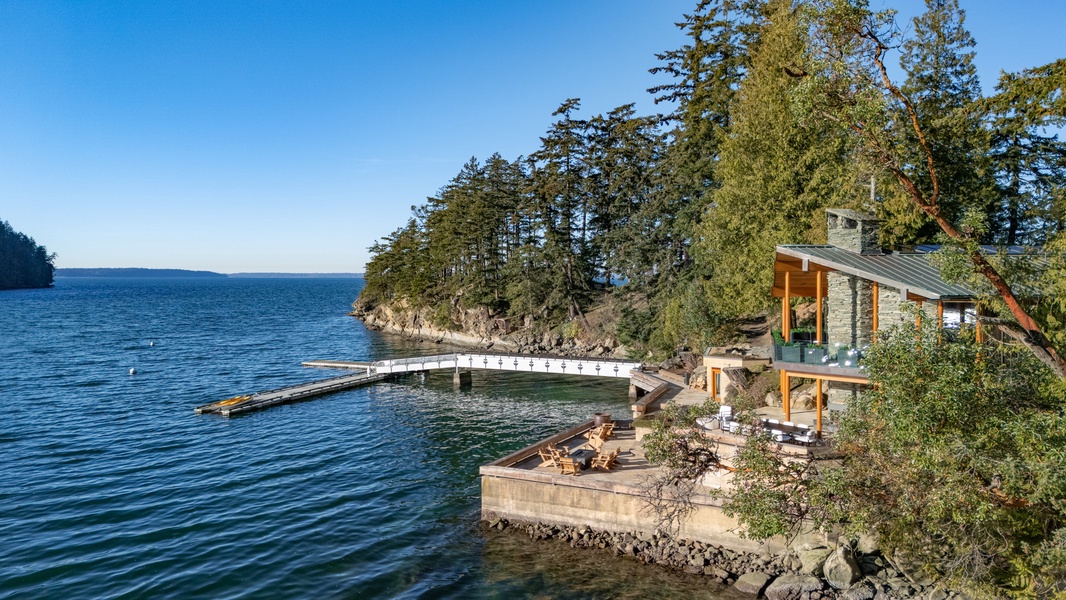 Stunning waterfront retreat with private dock and fire pit overlooking pristine lake waters surrounded by towering evergreens.