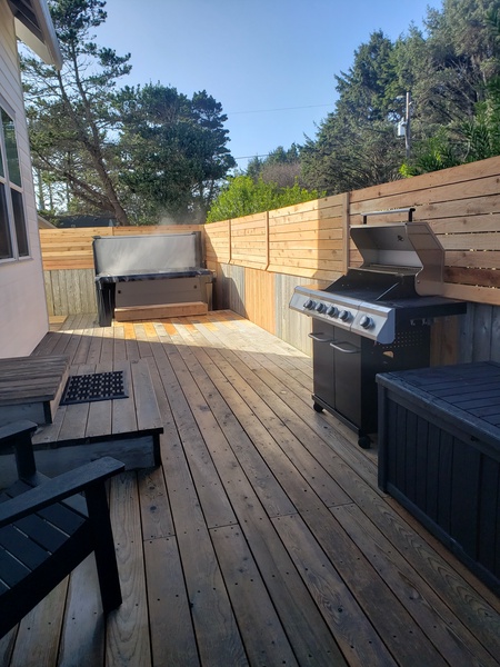 Large side deck area with gas BBQ, outdoor storage, and hot tub