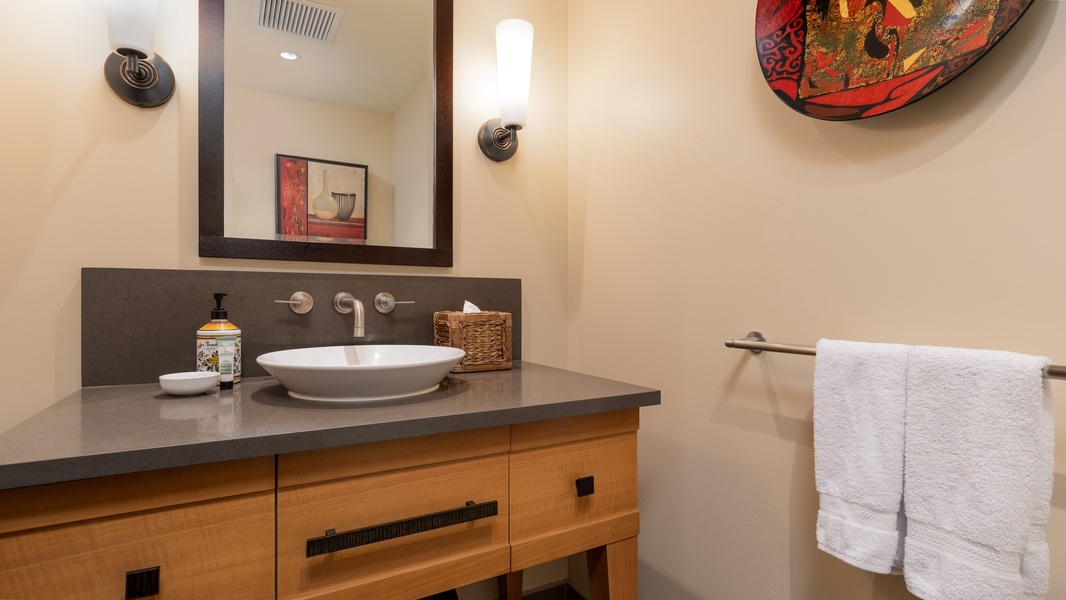 A half bath with sleek decorations and ample lighting.