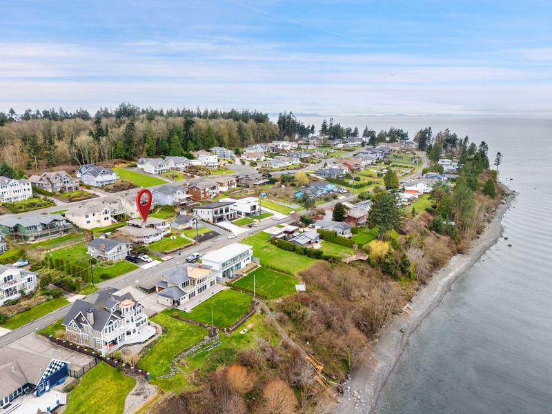 Coastal community nestled along the shoreline with well-maintained homes and tree-lined streets near the water's edge.