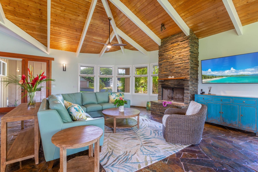 The main living space at Pohaku Villa features vaulted wood ceilings, stone fireplace accents, and plush seating for group gatherings.