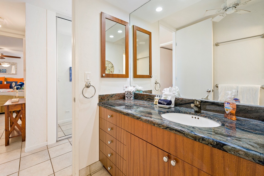 This elegant bathroom features a granite countertop with dual mirrors and warm wood cabinetry