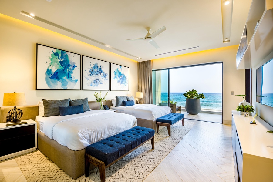 Relax in style in this airy guest bedroom with queen beds and a stunning view of the ocean.