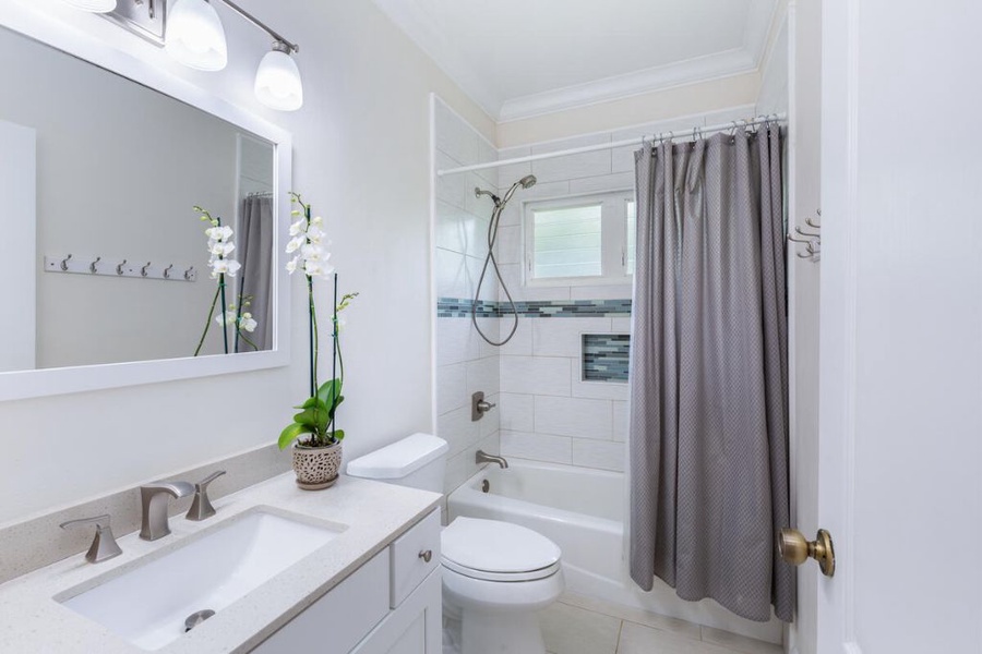 A bright shared bathroom for the guest bedrooms with a shower/tub combo and a single vanity