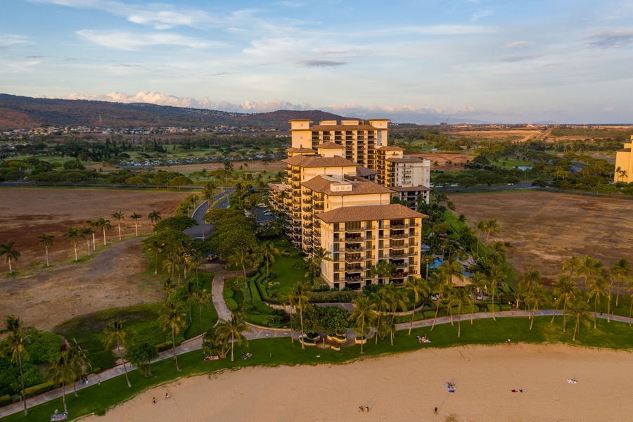 Beachfront resort towers rise from golden sands, surrounded by tropical palms and manicured grounds in this stunning coastal setting.