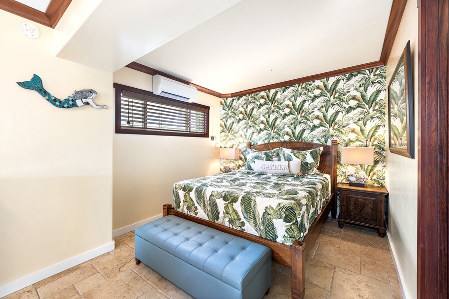 Tropical wallpaper and a soft palette create a stylish escape in this queen bedroom with bench seating.