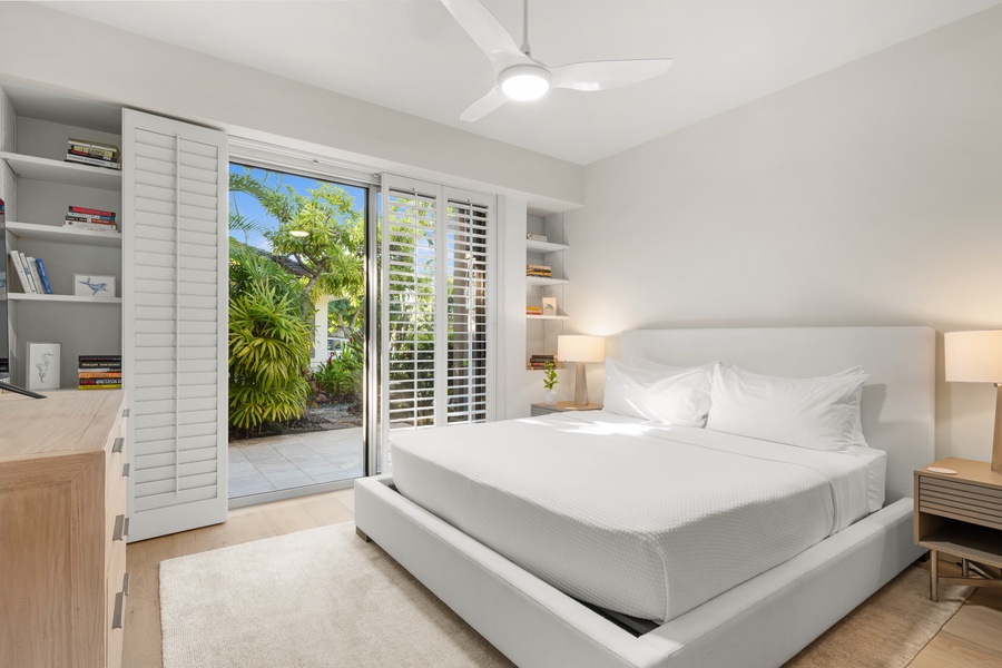 Drift off in your lower level bedroom sanctuary with a private patio and peaceful garden views beyond glass doors.