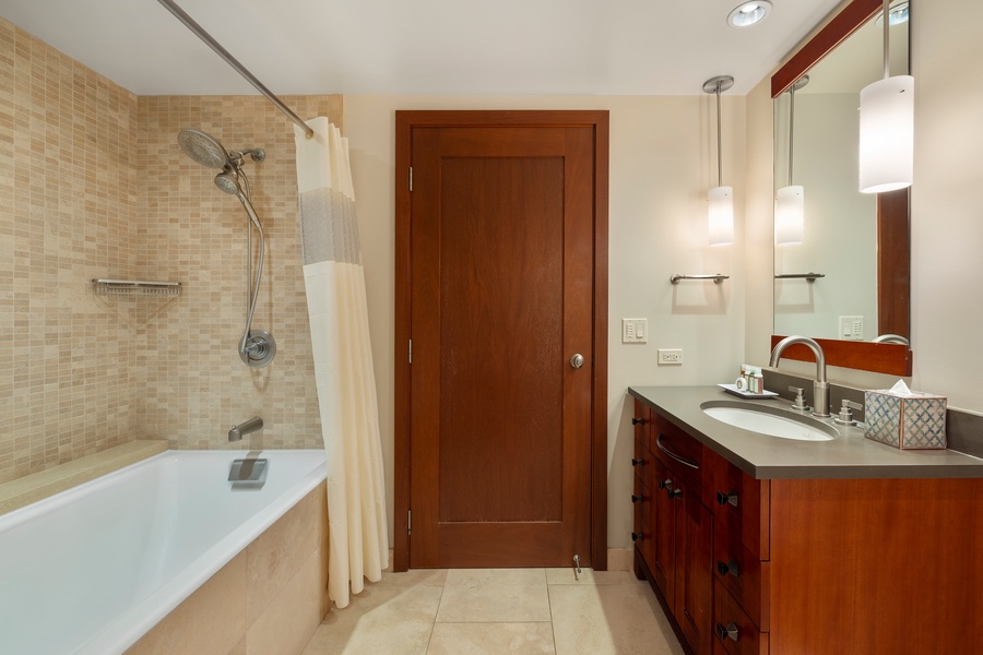 Warm, well-lit second bathroom with a spacious vanity and a bathtub.