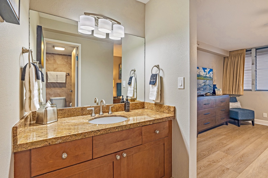 The bathroom features a sleek granite countertop and a well-lit vanity, providing a comfortable space to refresh.