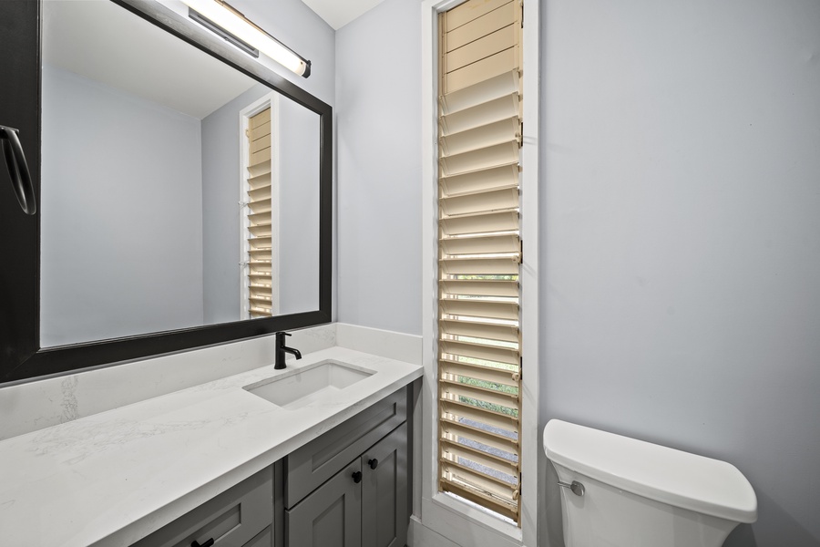 Bathroom with a sleek vanity, louvered window, and modern fixtures.