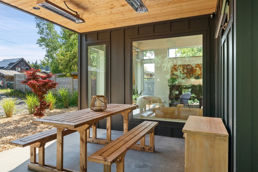 Enjoy all-season dining under a covered patio with picnic seating, patio heaters, and lush backyard views.