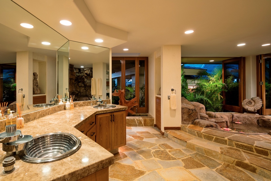 Palatial primary bath with dual vanity, fabulous rock soaking tub, walk-in shower, and privacy commode.