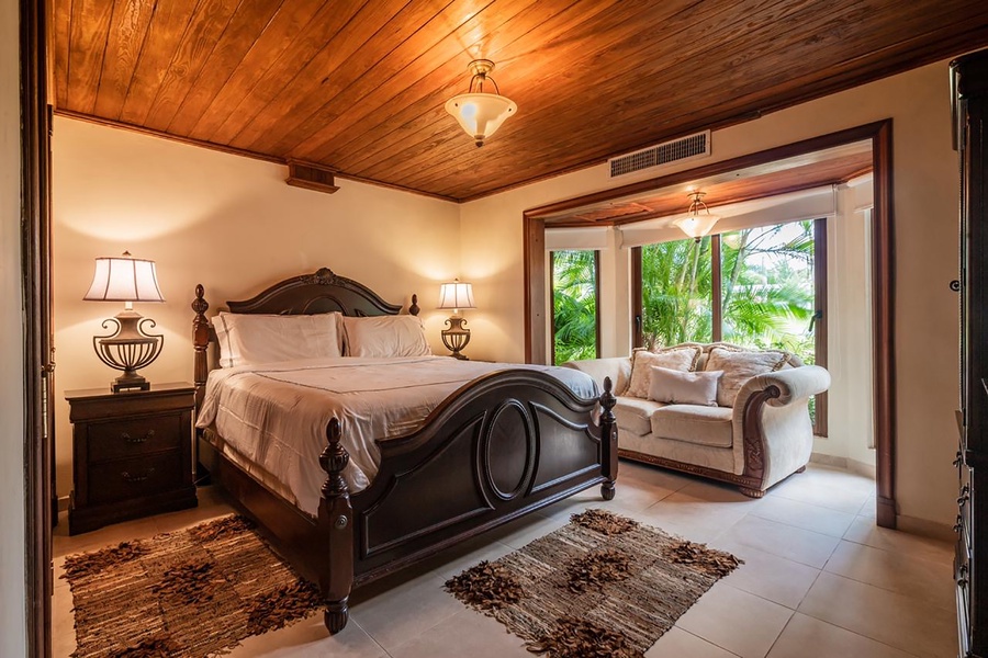 Fifth guest bedroom featuring a plush bed and seating, and serene views of the surrounding greenery.