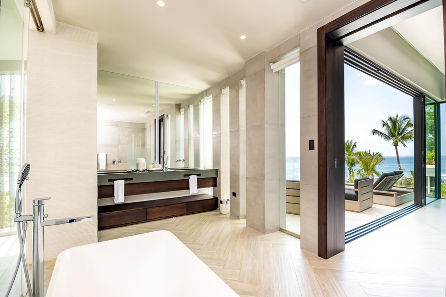 Elegant ensuite bathroom, complete with a soaking tub, dual vanities, and floor-to-ceiling windows offering breathtaking ocean views.