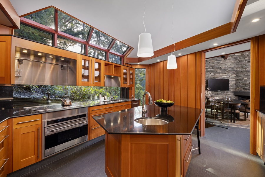 Your gourmet kitchen features rich wood cabinetry, granite countertops, and soaring ceilings with garden views through skylights.