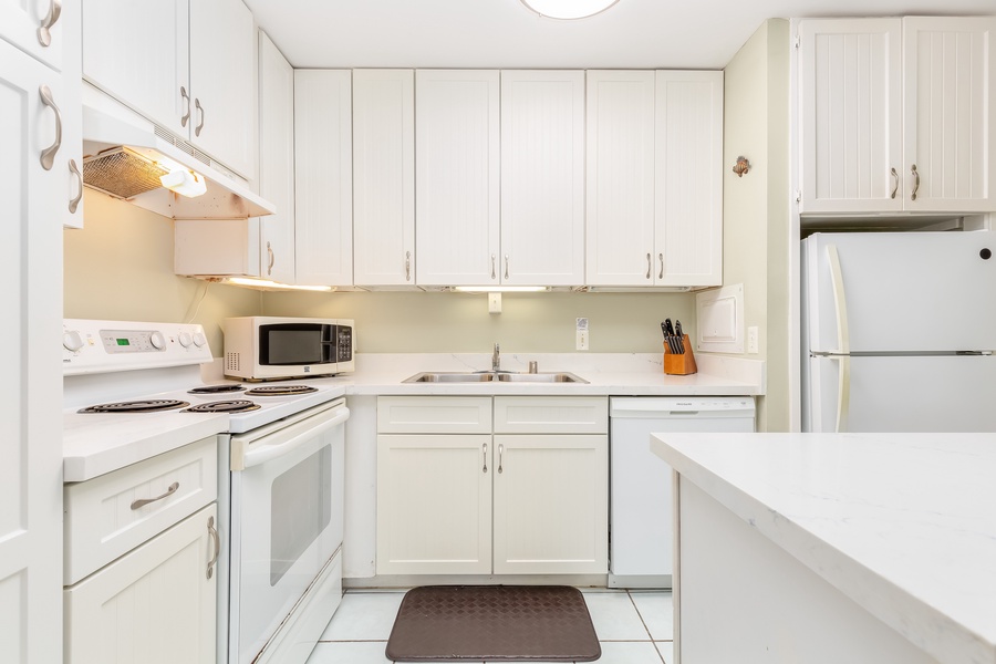 Ample appliances and tools with white cabinetry & counters.