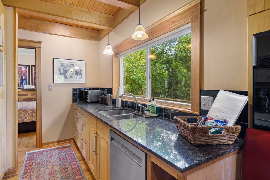 Bright and functional kitchen with large windows overlooking lush greenery for a scenic cooking atmosphere.