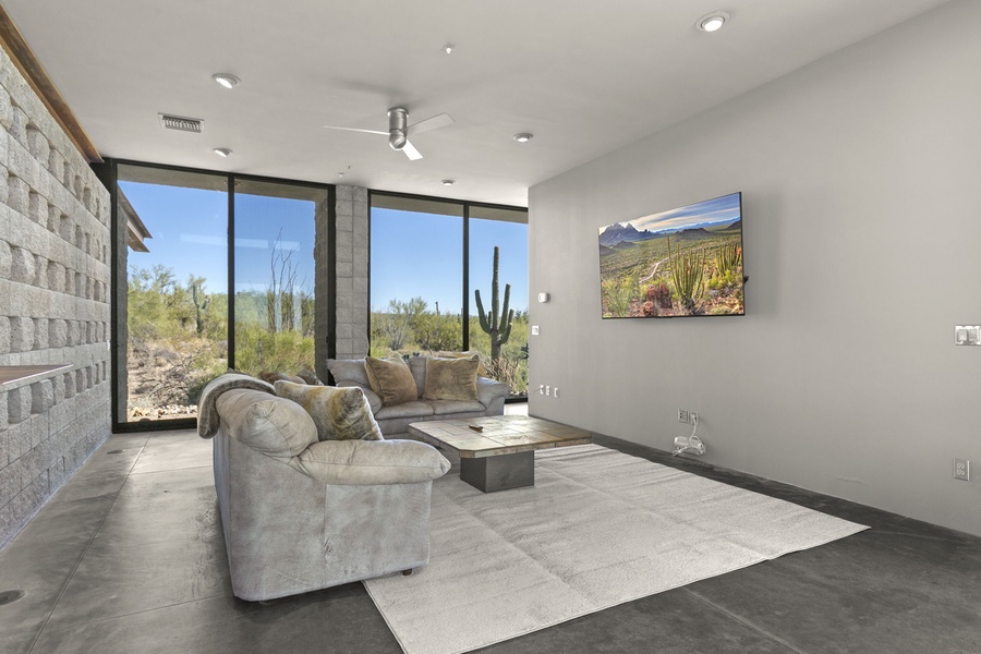 Relax in this minimalist informal living area with a smart TV, where the comfort of plush seating and the beauty of desert vistas come together to create a peaceful haven.