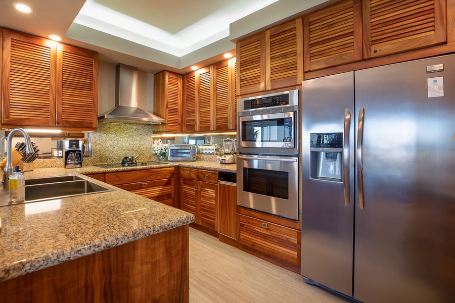 All stainless-steel appliances, Koa cabinets, granite countertops and a breakfast bar for two
