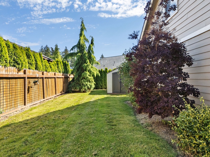 A large fenced side yard offers additional outdoor space surrounded by mature landscaping and privacy hedges.
