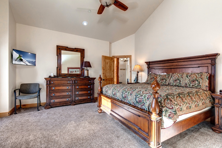 The master bedroom on the main floor has a king bed, TV, an en-suite bathroom, and access to a balcony.