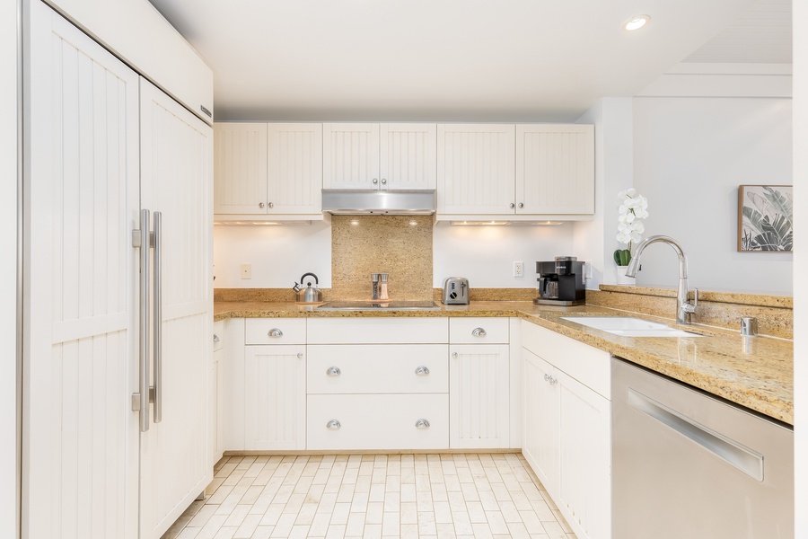 Your fully equipped kitchen awaits with granite countertops, white cabinetry, and modern appliances for preparing memorable meals during your stay.