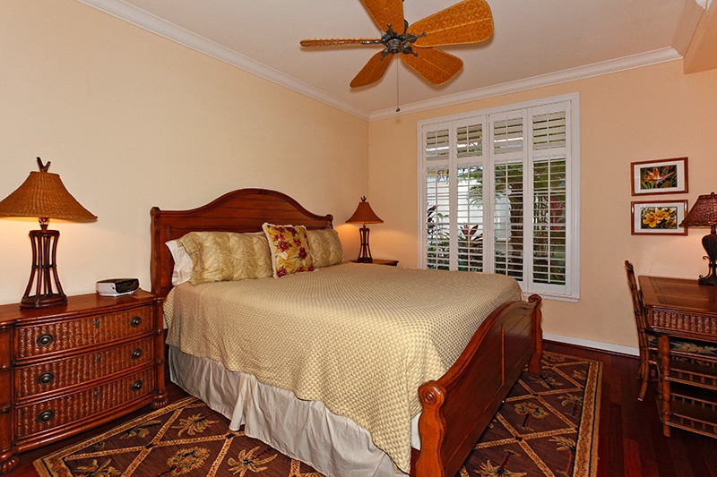The primary guest bedroom with ceiling fan, storage and luxurious bedding.
