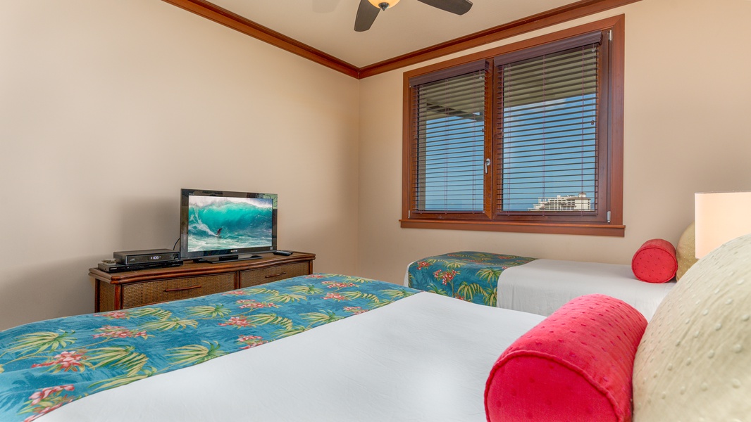 The second guest bedroom features one queen and one twin bed and a TV.