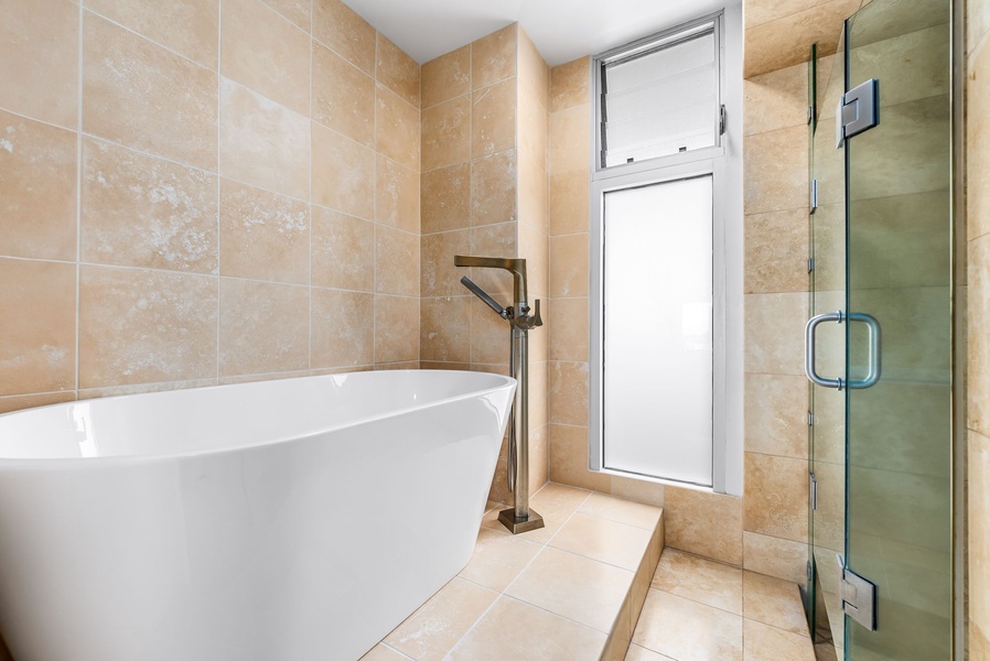 Contemporary glass shower and tilework provide a sleek, comfortable setting, combining function with a luxury feel.