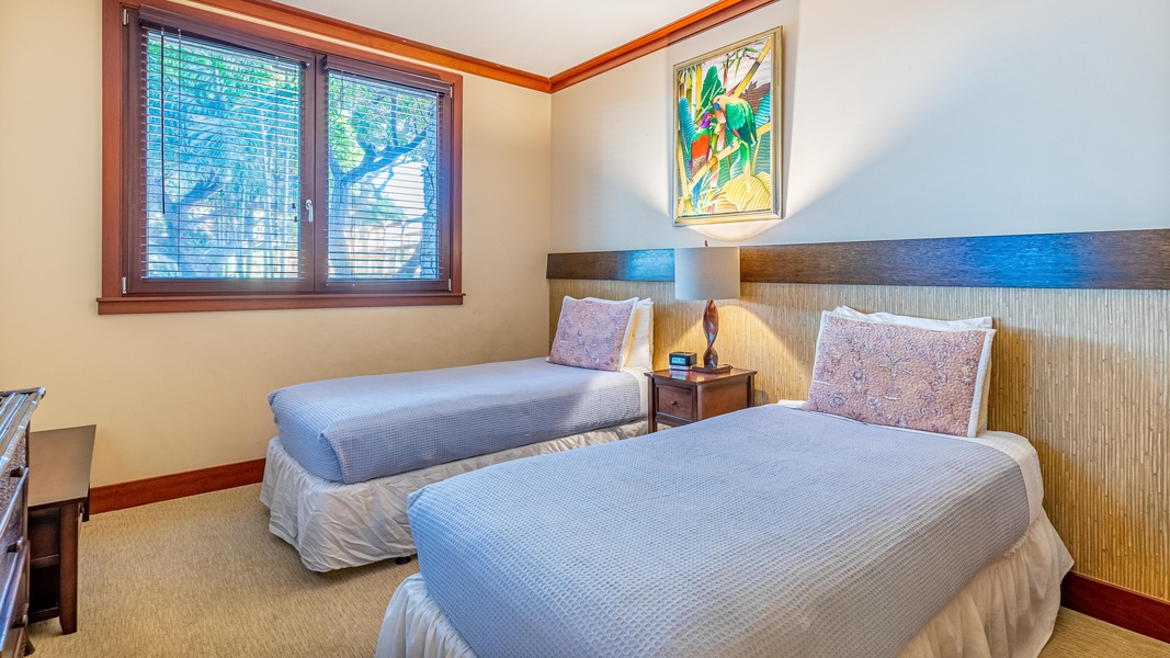 The second guest bedroom with twin beds, dresser, TV, and nightstand in the middle of both beds.