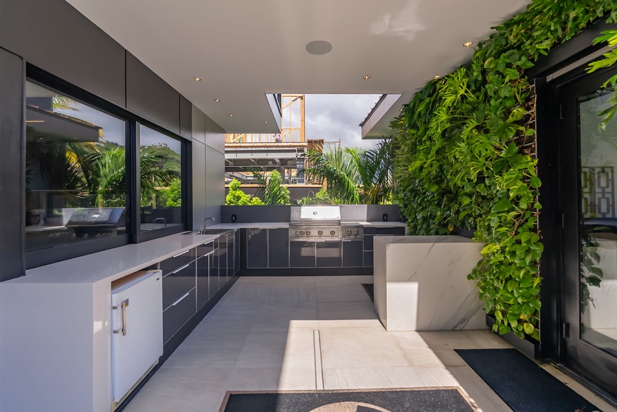 Outdoor kitchen framed by lush greenery and clean modern finishes.